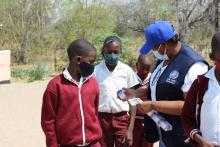 WHO staff distributing sample containers from Parakarungu Primary school learners 