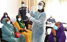 L'épidémiologiste de l'OMS montre aux femmes conviées à la réunion, comment le test rapide se fait