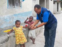 WHO staff, Dr. William Mwengee, checking for a finger mark on an eligible staff