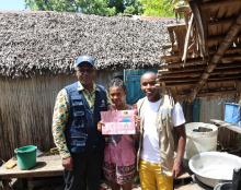 Jacqueline tenant fièrement sa carte de bénéficiaire du projet de la CSU, pose avec le Représentant de l'OMS Madagascar et le Médecin inspecteur de Sainte-Marie
