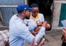 Le Ministre de la Santé Prof Benjamin Hounkpatin tenant vaccinant un enfant cible contre la Polio après avoir jugulé un cas de rrefus des parents