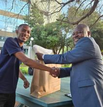 Staff Association President Sean Maswabi presents a token of appreciation to Mr Wilfred
