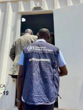 Officials enter a mobile clinic during a visit showcasing equipment delivered by WHO.