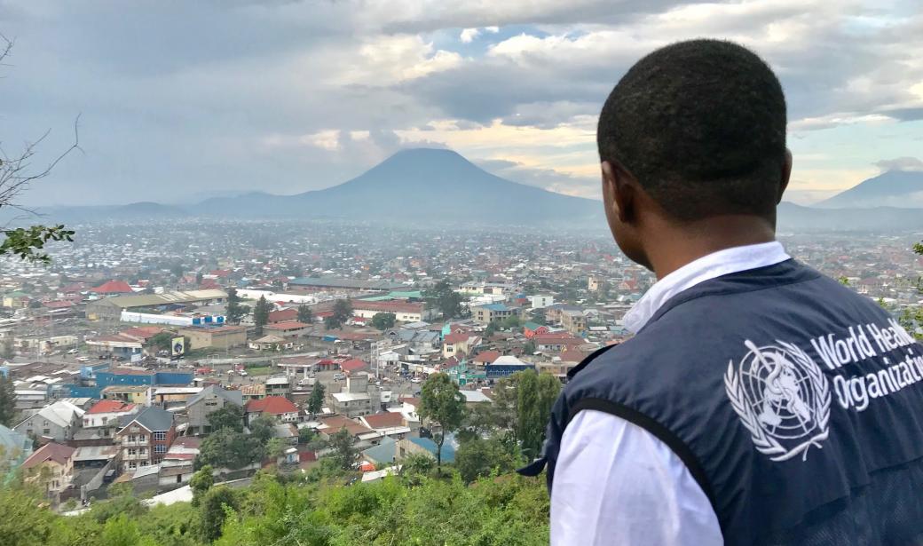 A WHO worker stands on a hill overlooking the city