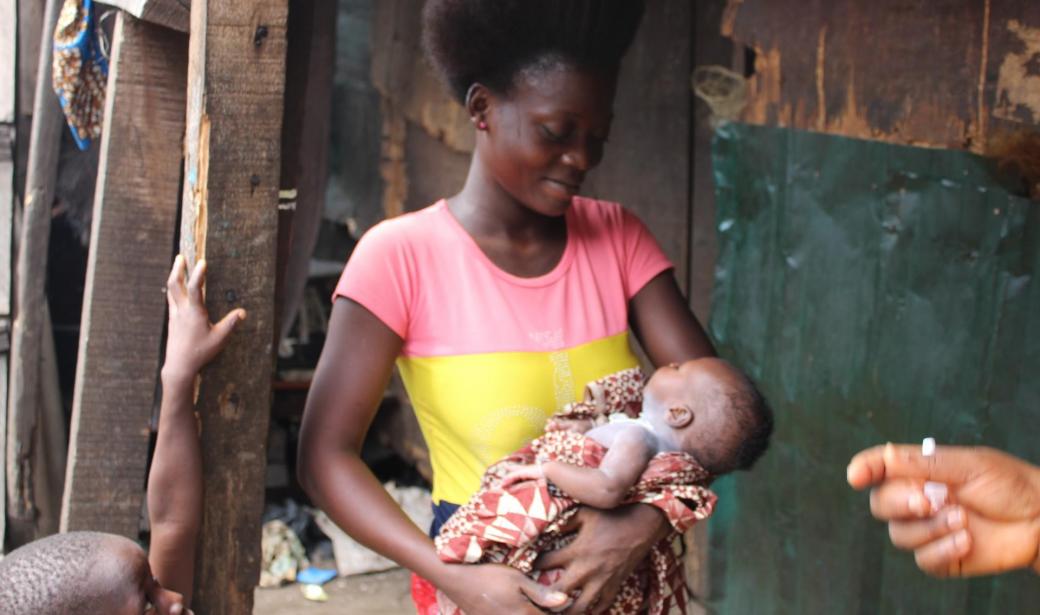 22-year-old Bose Awhanjojbe cradles her two-week-old daughter, Florence Awhanjojbe, after receiving vaccines in Makoko Community of Lagos
