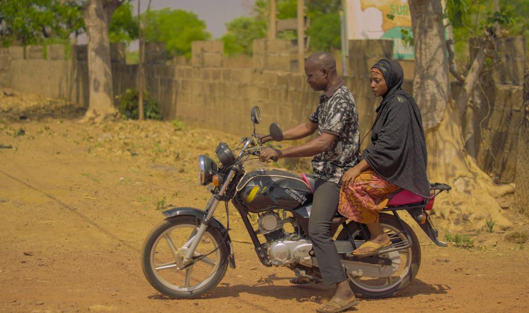 Bilikisu and Bello riding on a bike to Rubochi community.jpg