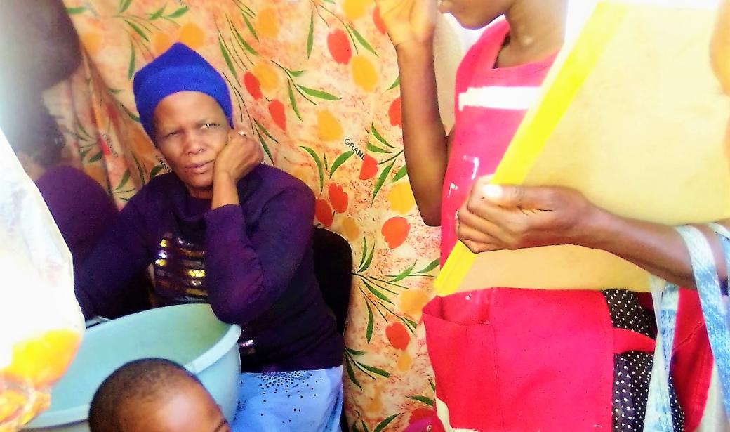 Red Cross Volunteers sharing information at a household in the Informal Settlement 