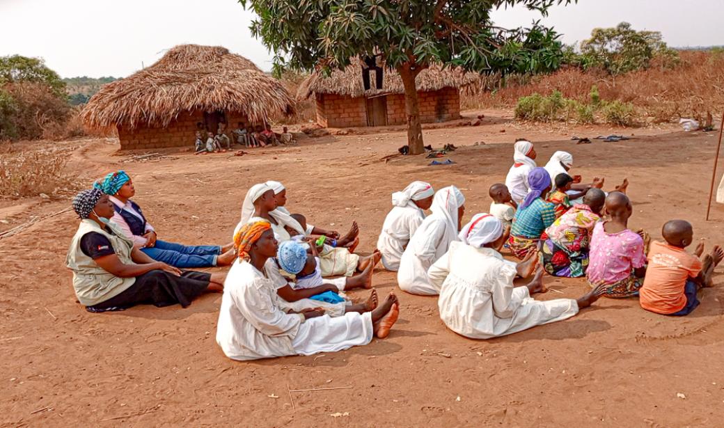 Scholastique Ngalula et sa collègue de l'UNICEF sont assises en arrière-plan et participent au culte des Bapostolo afin de les sensibiliser à la vaccination à Kaniama. Crédit photo, OMS RDC