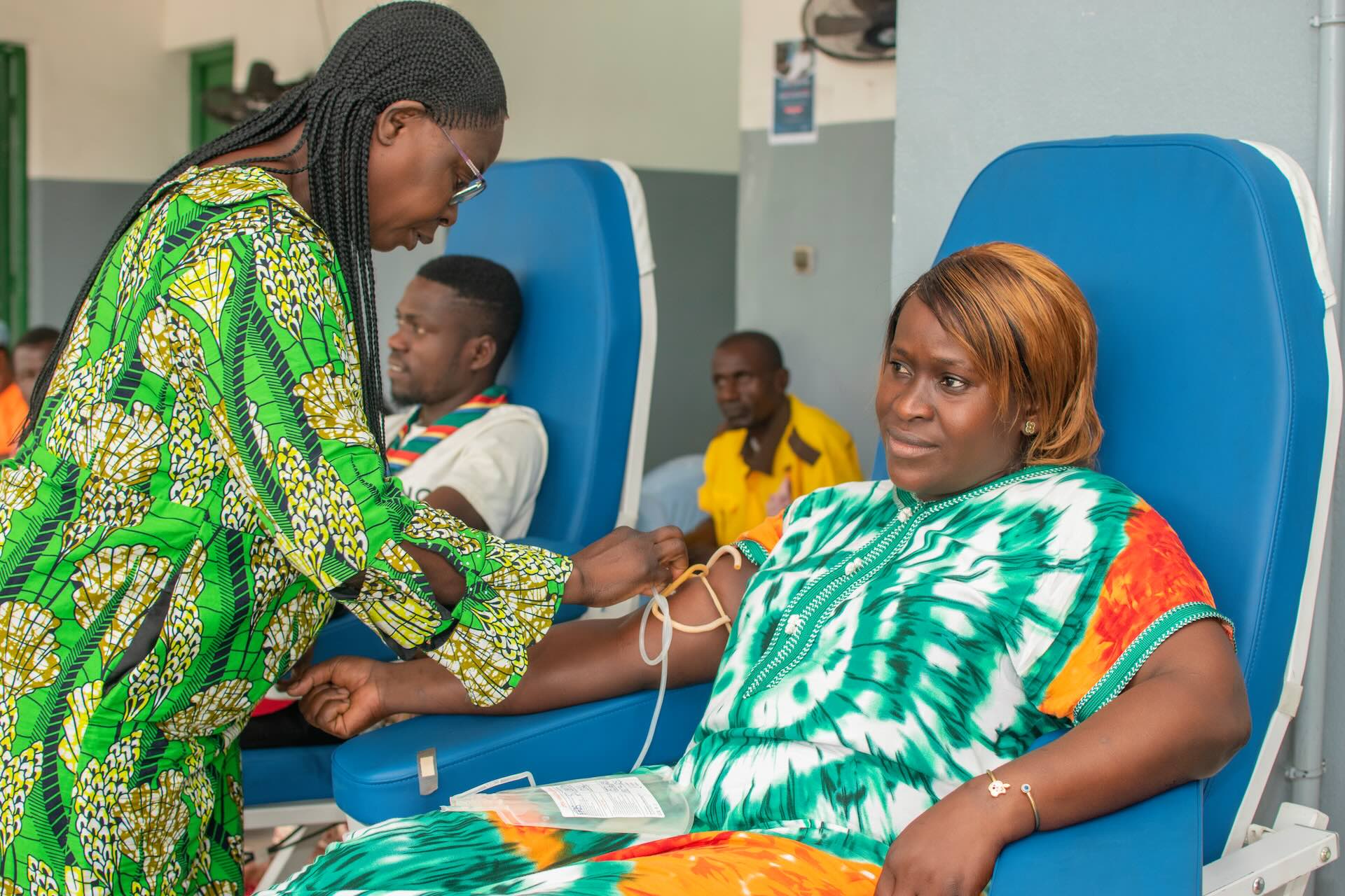 A health worker attends to a seated donor during a blood donation session